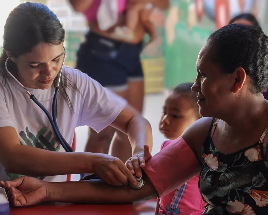 Saúde Comunitária: Fé e Cuidado Técnico Voluntária de saúde da Igreja El Shaday verificando a pressão arterial de uma senhora em Parnaíba.